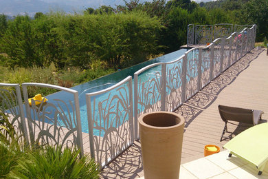 Inspiration pour une grande piscine à débordement et avant design rectangle avec une terrasse en bois.