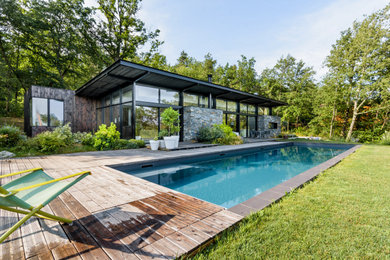 Diseño de piscina actual rectangular en patio trasero con entablado
