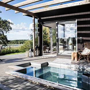 Design ideas for a mid-sized scandinavian side yard custom-shaped pool in Stockholm with a hot tub and decking.
