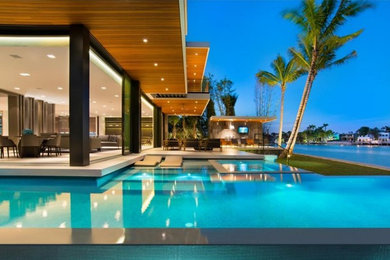 Example of a large minimalist backyard infinity hot tub design in Miami