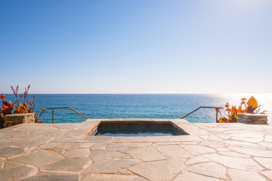 Esempio di una piscina minimal dietro casa con una vasca idromassaggio e pavimentazioni in pietra naturale
