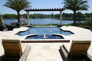Large minimalist backyard concrete paver and custom-shaped pool fountain photo in Orlando