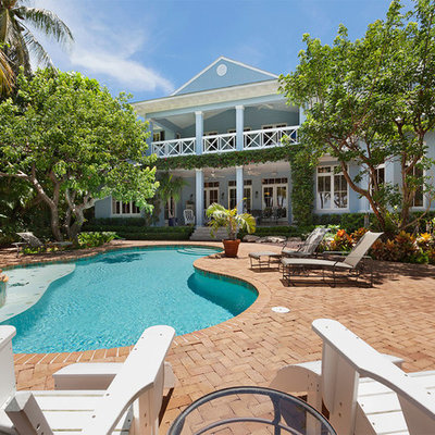 Example of a mid-sized island style backyard brick and kidney-shaped natural hot tub design in Other