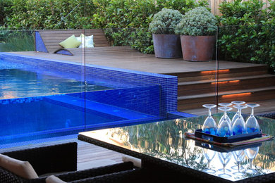 Exemple d'une piscine à débordement et arrière de taille moyenne et sur mesure avec une terrasse en bois.