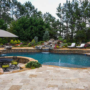 Inspiration for a large traditional backyard custom-shaped natural pool in Atlanta with a water feature and natural stone pavers.