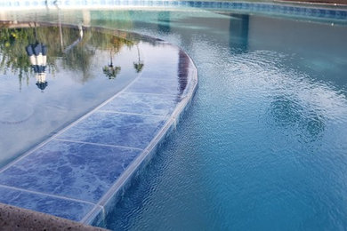 Imagen de piscina infinita mediterránea de tamaño medio tipo riñón en patio trasero con losas de hormigón