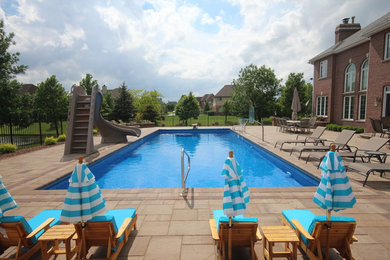 На фото: большой прямоугольный, спортивный бассейн на заднем дворе в классическом стиле с водной горкой с