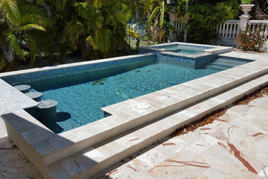 Immagine di una piscina naturale tropicale rettangolare di medie dimensioni e dietro casa con una vasca idromassaggio e pavimentazioni in pietra naturale