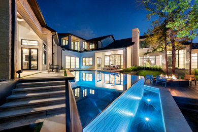 Example of a large trendy backyard concrete and custom-shaped infinity pool design in Dallas