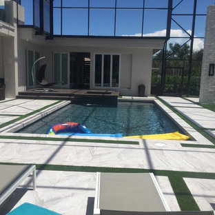 Esempio di un'ampia piscina naturale minimalista personalizzata dietro casa con pedane
