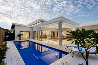 Diseño de piscina actual grande rectangular en patio trasero con adoquines de piedra natural