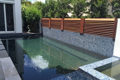 Design ideas for a modern back rectangular lengths swimming pool in Miami with a water feature.