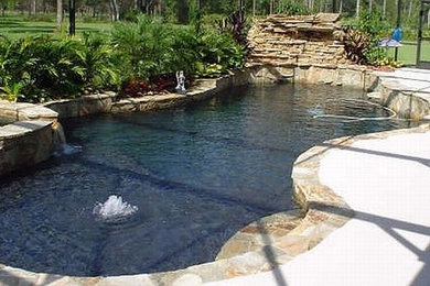 Mid-sized island style backyard stone and custom-shaped hot tub photo in Orlando