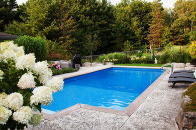 This is an example of a large world-inspired back rectangular lengths swimming pool in Toronto with a pool house and stamped concrete.