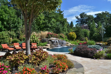 Imagen de piscina con fuente exótica grande a medida en patio trasero