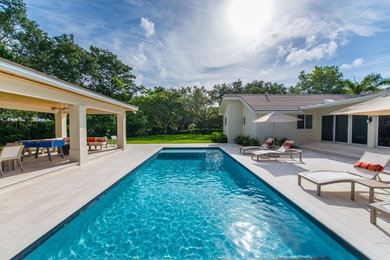 Inspiration for a large contemporary backyard stone and rectangular pool remodel in Miami