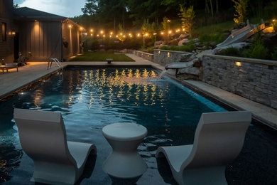 Imagen de piscina moderna rectangular en patio trasero con adoquines de piedra natural