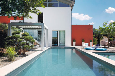 Ejemplo de piscina natural minimalista de tamaño medio rectangular con adoquines de hormigón