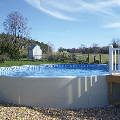 Example of a mid-sized classic backyard round aboveground pool design in Other