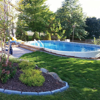 Example of a mid-sized trendy backyard concrete and round aboveground pool design in Cleveland