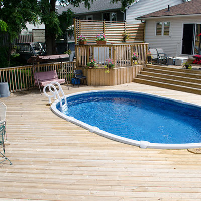 Example of a mid-sized classic backyard round aboveground pool design in Toronto
