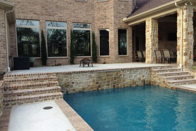 Imagen de piscina con fuente alargada de estilo americano de tamaño medio rectangular en patio trasero con adoquines de ladrillo