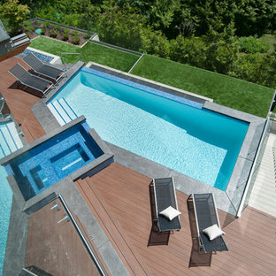 Esempio di una piscina a sfioro infinito minimal personalizzata dietro casa con una vasca idromassaggio e pedane