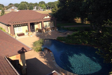 Large contemporary back kidney-shaped natural swimming pool in Dallas with a pool house and natural stone paving.