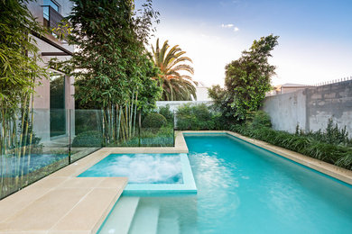 Exemple d'une piscine à débordement tendance sur mesure avec des pavés en béton.