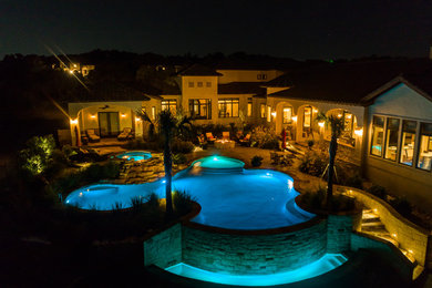 Imagen de piscina con fuente infinita mediterránea grande a medida en patio trasero con suelo de hormigón estampado