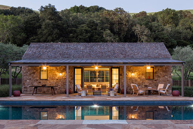 This is an example of a rustic back rectangular lengths swimming pool in San Francisco with a pool house.