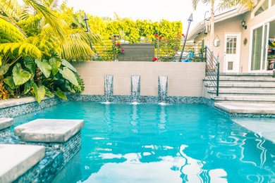 Moderner Schwimmteich hinter dem Haus in L-Form mit Wasserspiel und Betonboden in Orange County