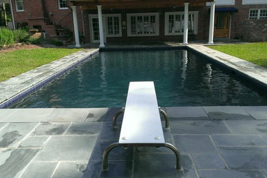 Imagen de piscina grande rectangular en patio trasero con adoquines de piedra natural