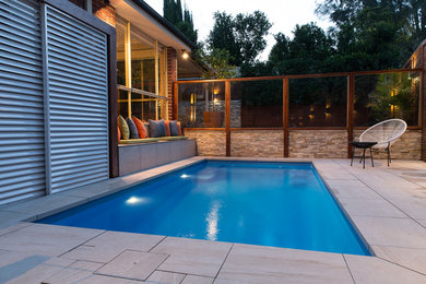 Foto de piscina actual pequeña rectangular en patio con adoquines de piedra natural