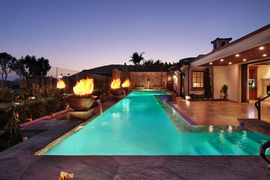 Modelo de piscina con fuente alargada mediterránea grande a medida en patio trasero con adoquines de piedra natural