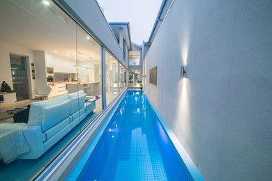 Modelo de piscina alargada minimalista de tamaño medio rectangular en patio lateral con entablado