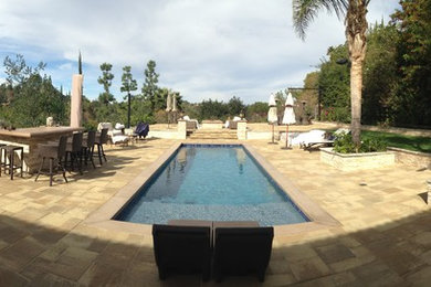 На фото: большой прямоугольный, спортивный бассейн на заднем дворе в стиле модернизм с покрытием из каменной брусчатки