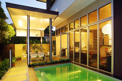 Пример оригинального дизайна: спортивный, прямоугольный бассейн среднего размера на боковом дворе в стиле модернизм с домиком у бассейна и мощением тротуарной плиткой