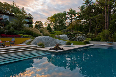 Esempio di una grande piscina monocorsia minimal rettangolare dietro casa con una vasca idromassaggio e lastre di cemento
