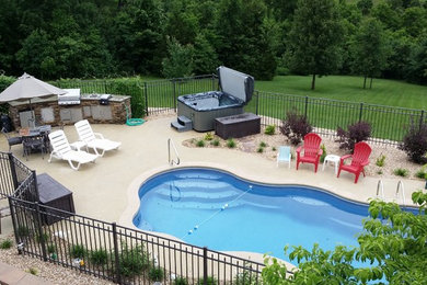 Diseño de piscina con fuente natural clásica grande a medida en patio trasero con adoquines de hormigón
