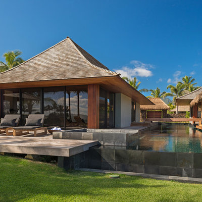 Hot tub - large tropical courtyard rectangular infinity hot tub idea in Other with decking