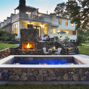 This is an example of a small country backyard rectangular natural pool in Boston with a hot tub and natural stone pavers.
