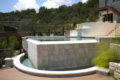 На фото: большой прямоугольный бассейн-инфинити на заднем дворе в современном стиле с джакузи и покрытием из каменной брусчатки