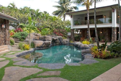 This is an example of a medium sized world-inspired back custom shaped natural swimming pool in Los Angeles with a water feature and natural stone paving.