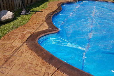 Ejemplo de piscina tradicional de tamaño medio a medida en patio trasero con adoquines de hormigón