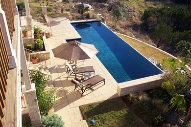 Pool - large contemporary backyard stone and rectangular infinity pool idea in Austin