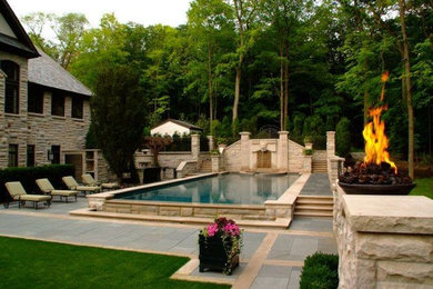 Large traditional back rectangular swimming pool in Chicago with a water feature.