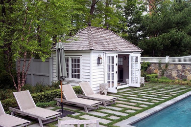 Ejemplo de casa de la piscina y piscina alargada tradicional grande rectangular en patio trasero con suelo de baldosas