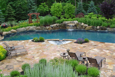 Mid-sized island style backyard stone and custom-shaped pool fountain photo in New York
