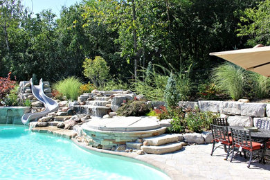 Large elegant backyard brick and custom-shaped hot tub photo in Toronto